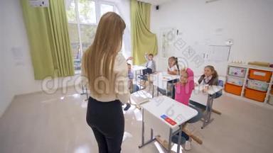 在学校的课堂教学中，女教育家和可爱的小学者在课桌旁交谈